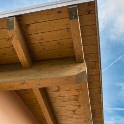 Corner,Of,House,With,Wooden,Beams,Against,Blue,Sky.